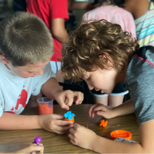 Two boys looking at and playing with an object on the table.