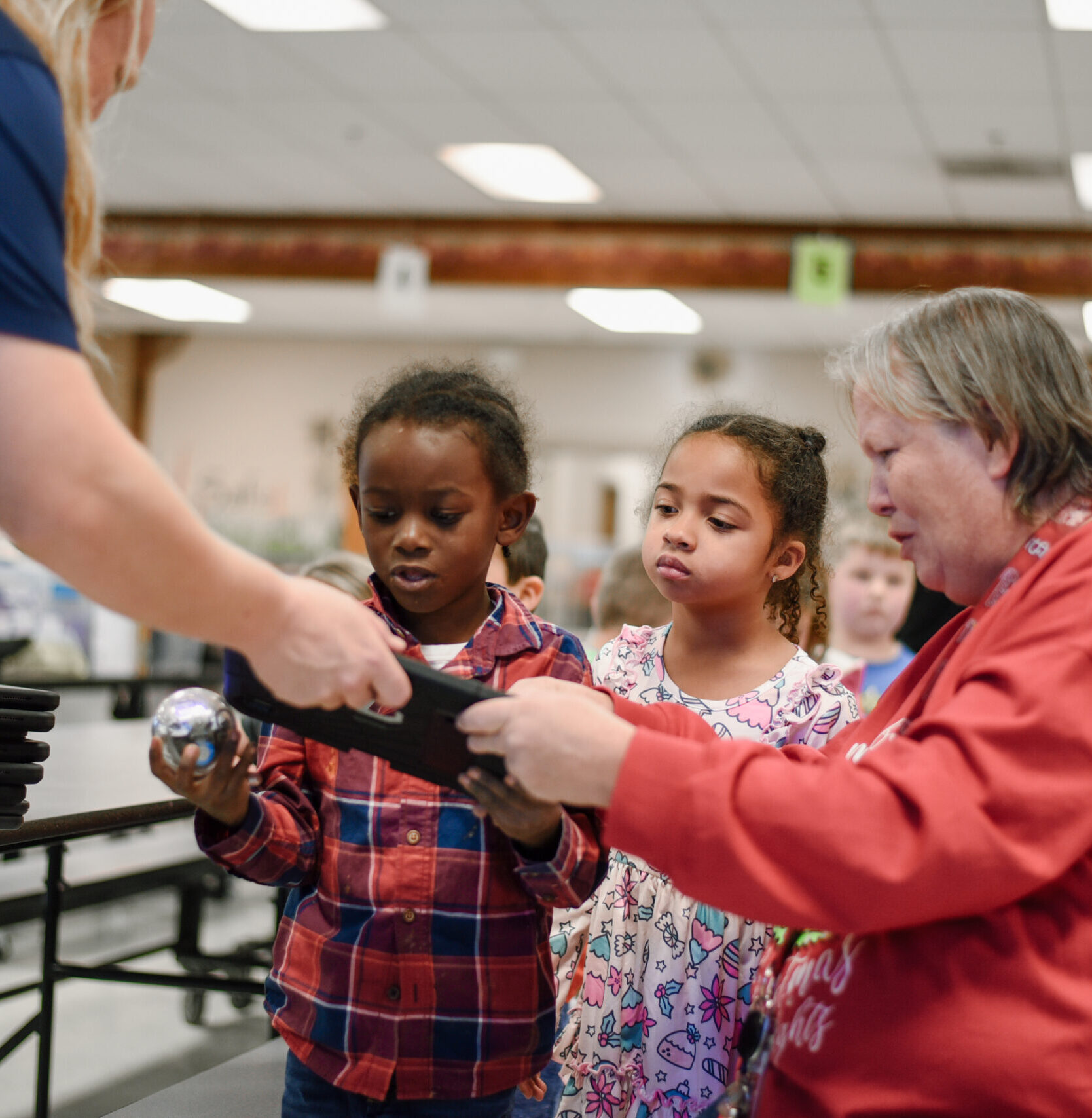 Stem educator and school teacher help two young students get set up with a robot ball.