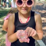 Girl showing an object to the camera.