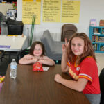 Girls at a table smiling at the camera